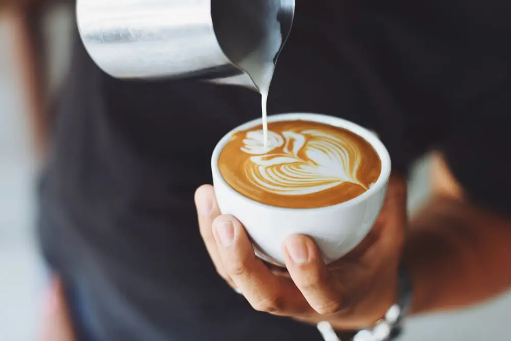 Barista versant un latte art soigné, contenu photogénique idéal pour Instagram